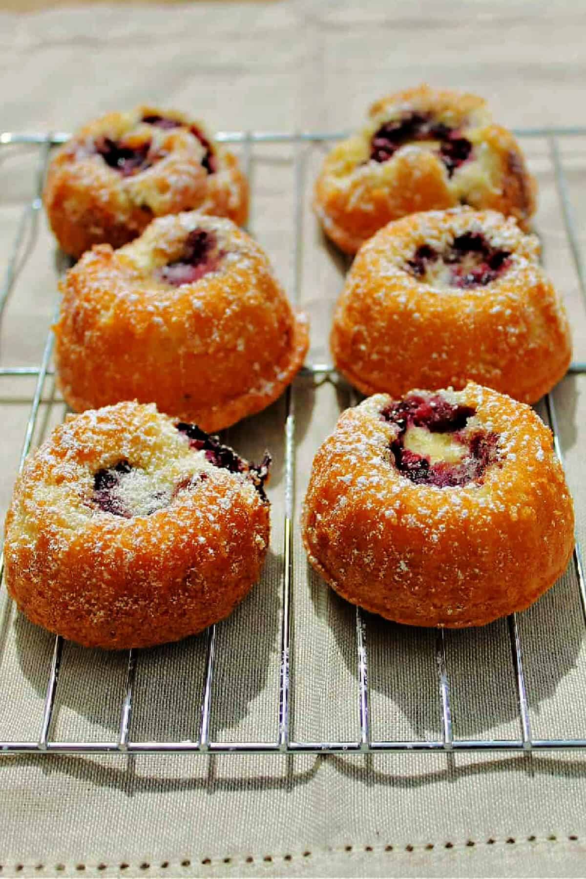 Little cakes with blackberry centre on a cooling rack.