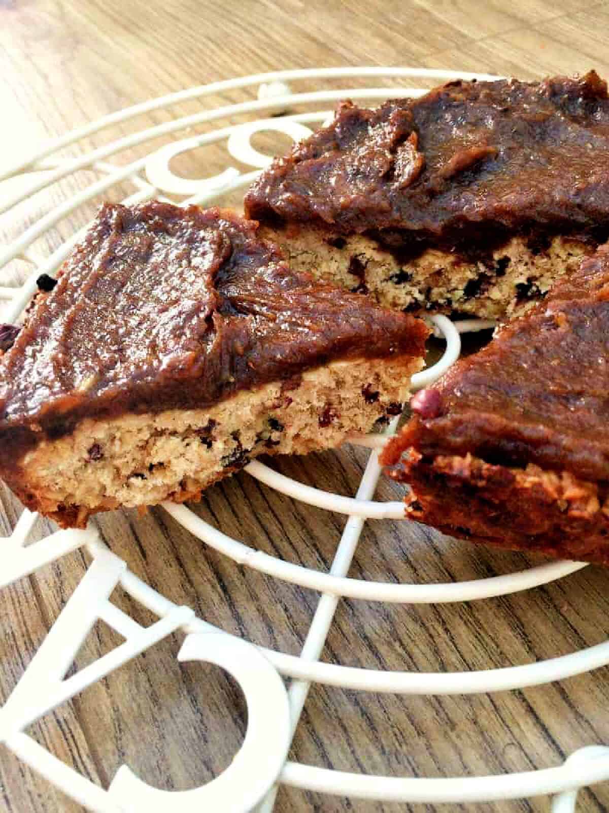 Triangle oat bar slice with cocoa nibs, with date caramel spread on top.
