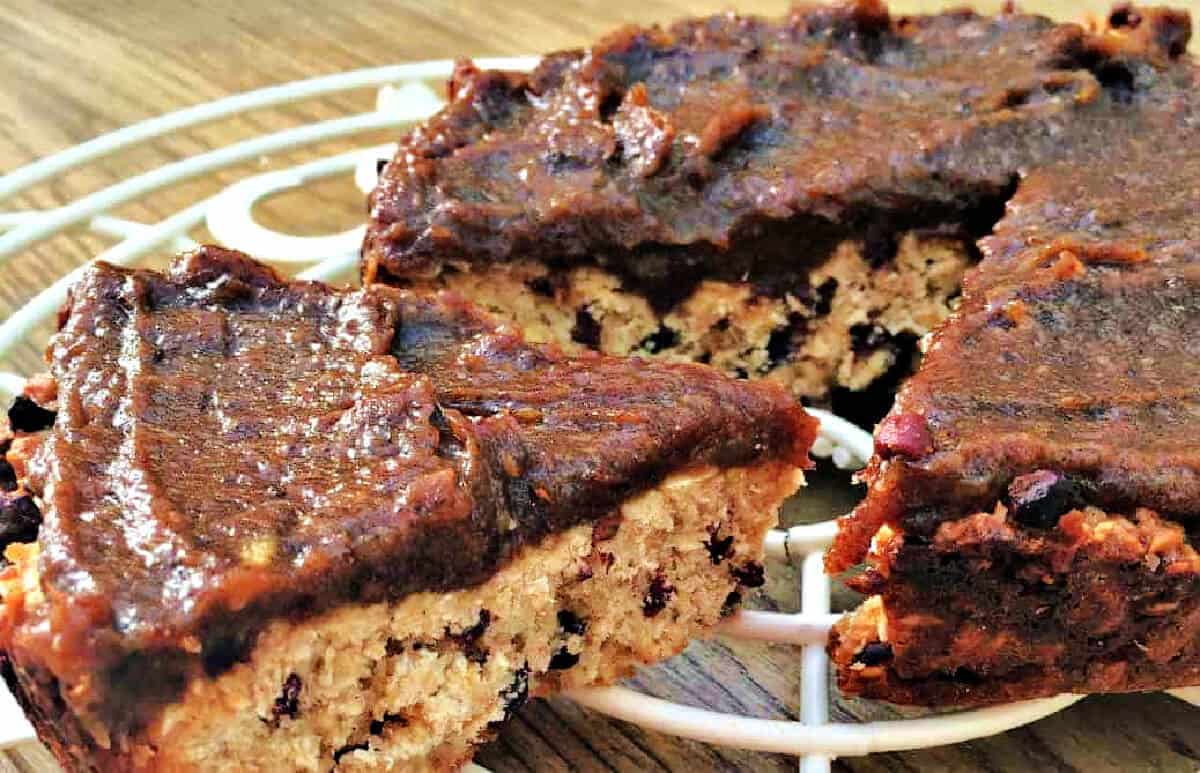 An oat bar with cocoa nibs with date caramel spread on top.