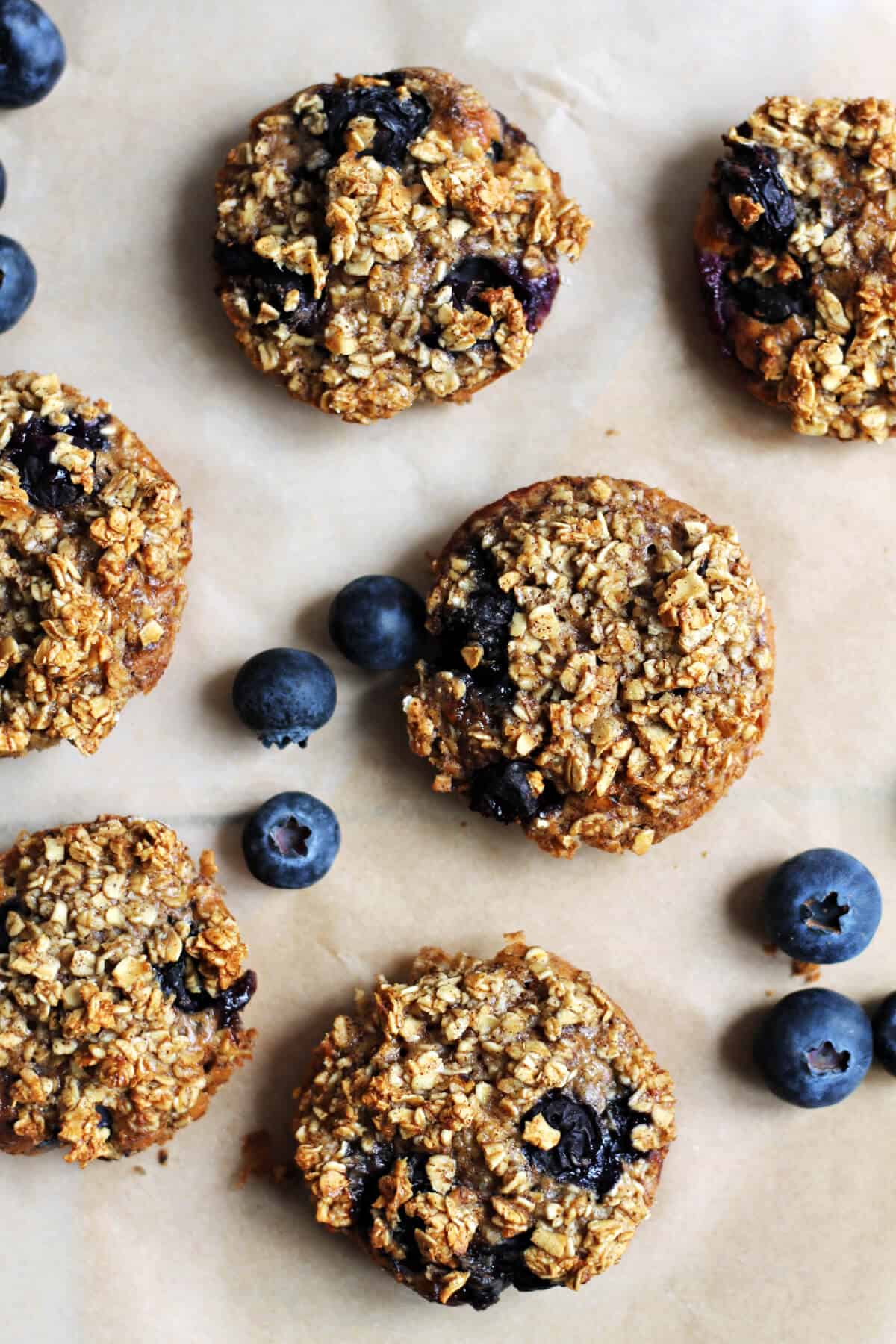 Oat cups on a sheet of baking paper, with fresh blueberries.