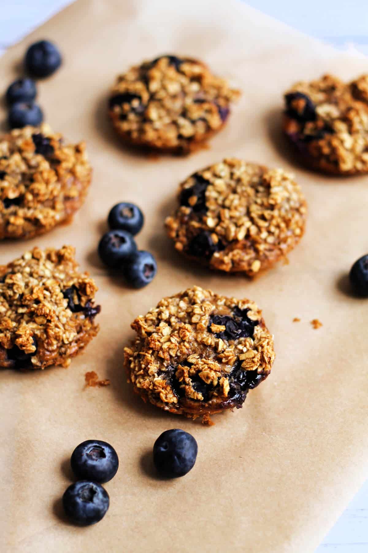 Mini baked oat cups on baking paper, with fresh blueberries.