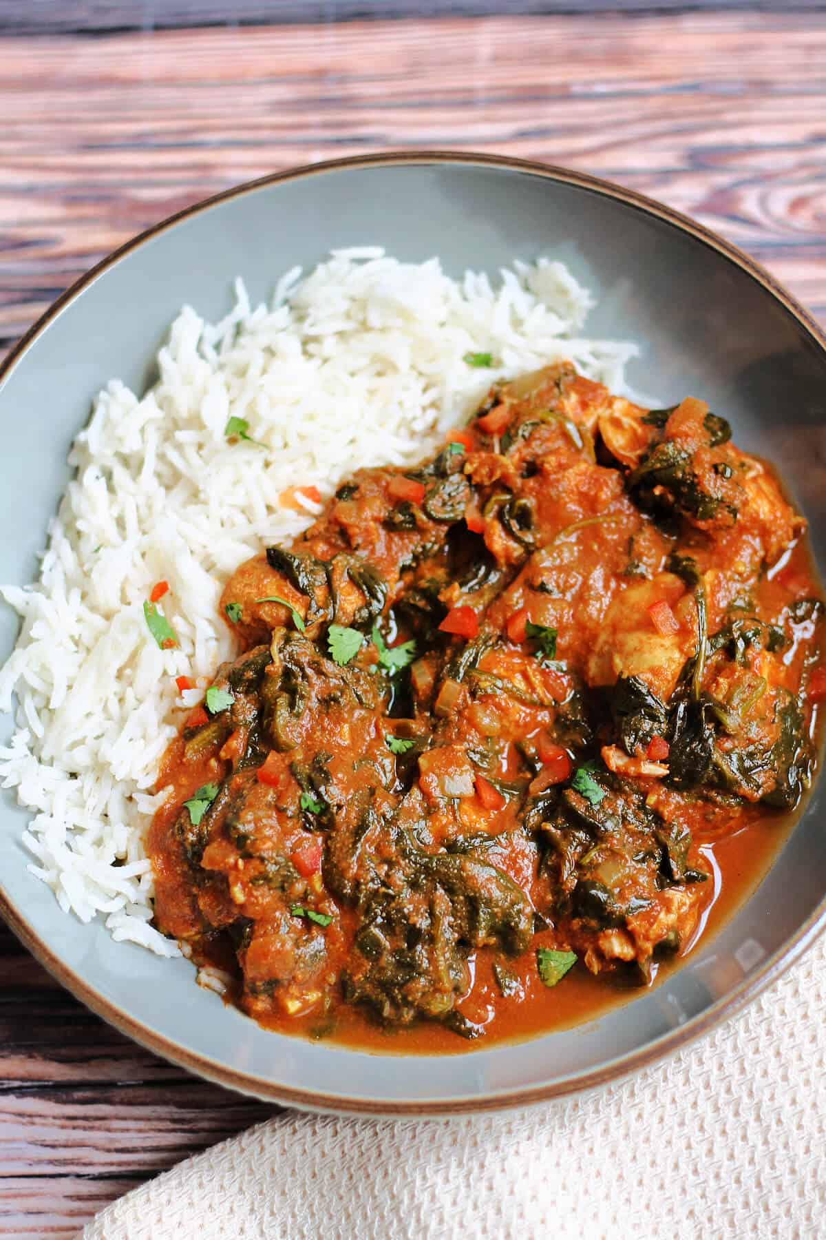 Chicken saag curry and rice in a grey bowl.