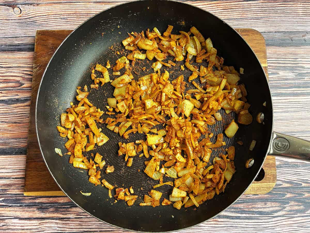 Onion, garlic and spices in frying pan.