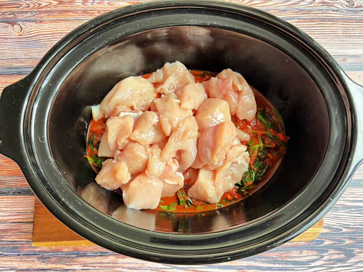 Slow cooker pot with diced chicken and curry sauce.