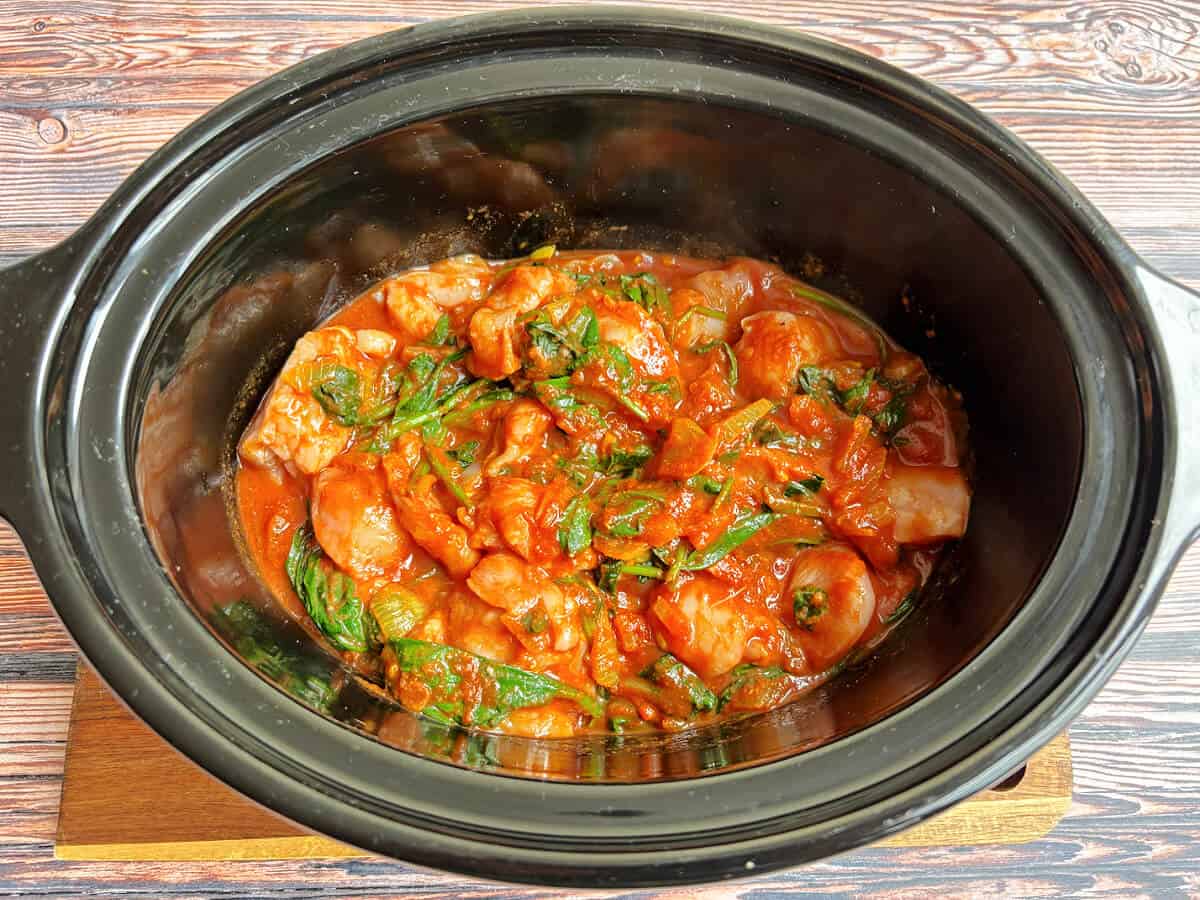 Chicken spinach curry ready to cook, in slow cooker pot.
