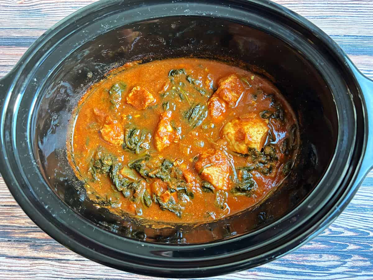 Cooked chicken saag curry in slow cooker pot.