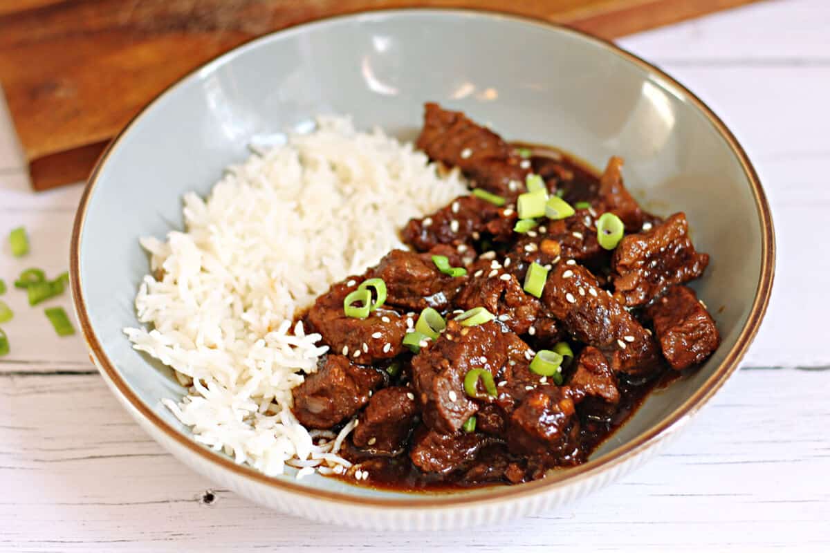 Tender beef in a rich glossy sauce with white rice in a grey bowl.