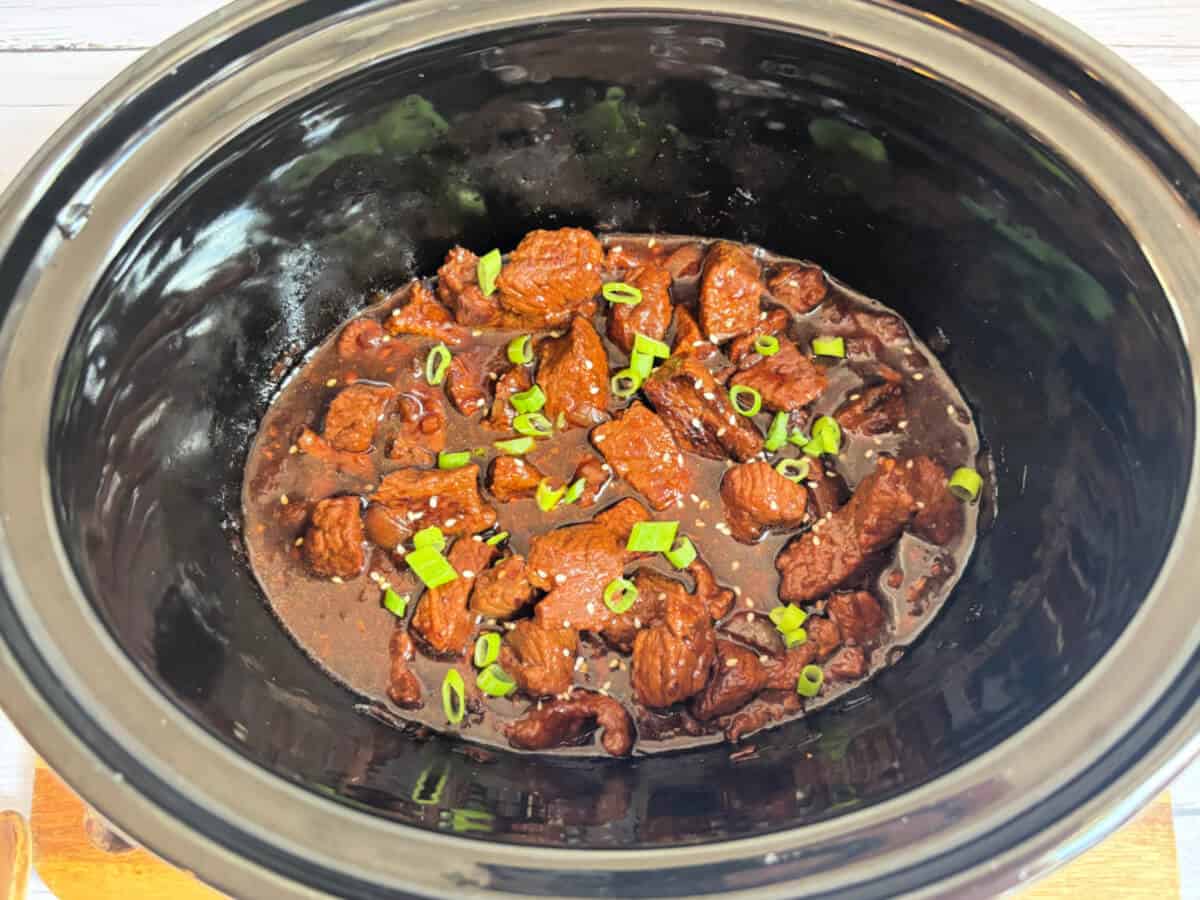 Cooked beef teriyaki with a thick sauce, garnished with chopped spring onions.