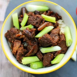 Overhead view of bowl with beef and spring onions on top.