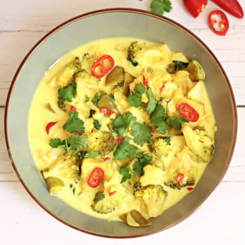 Grey bowl of vibrant fish curry garnished with fresh coriander and sliced red chilli.