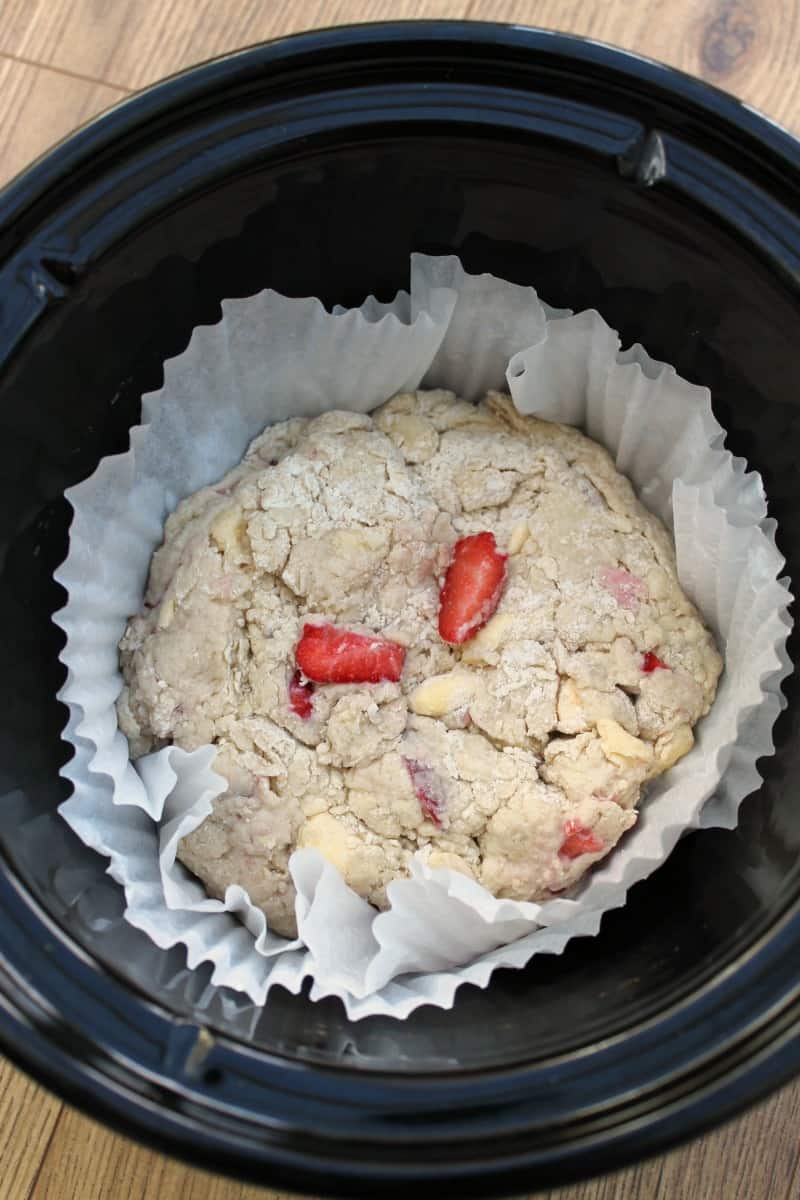 A strawberry scone mixture in paper case in slow cooker pot.