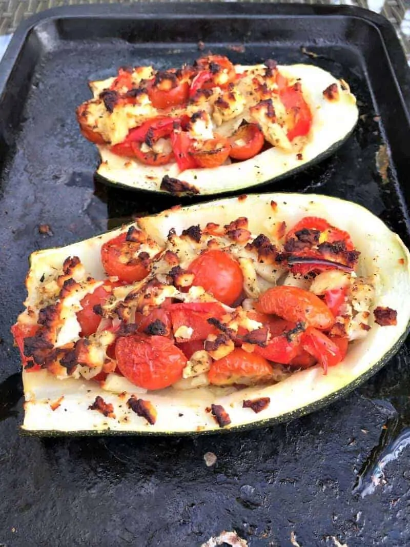 Stuffed courgettes with red pepper on baking tray.