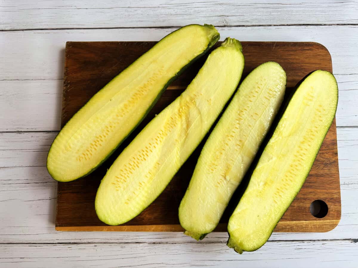 Halved courgettes on chopped board.