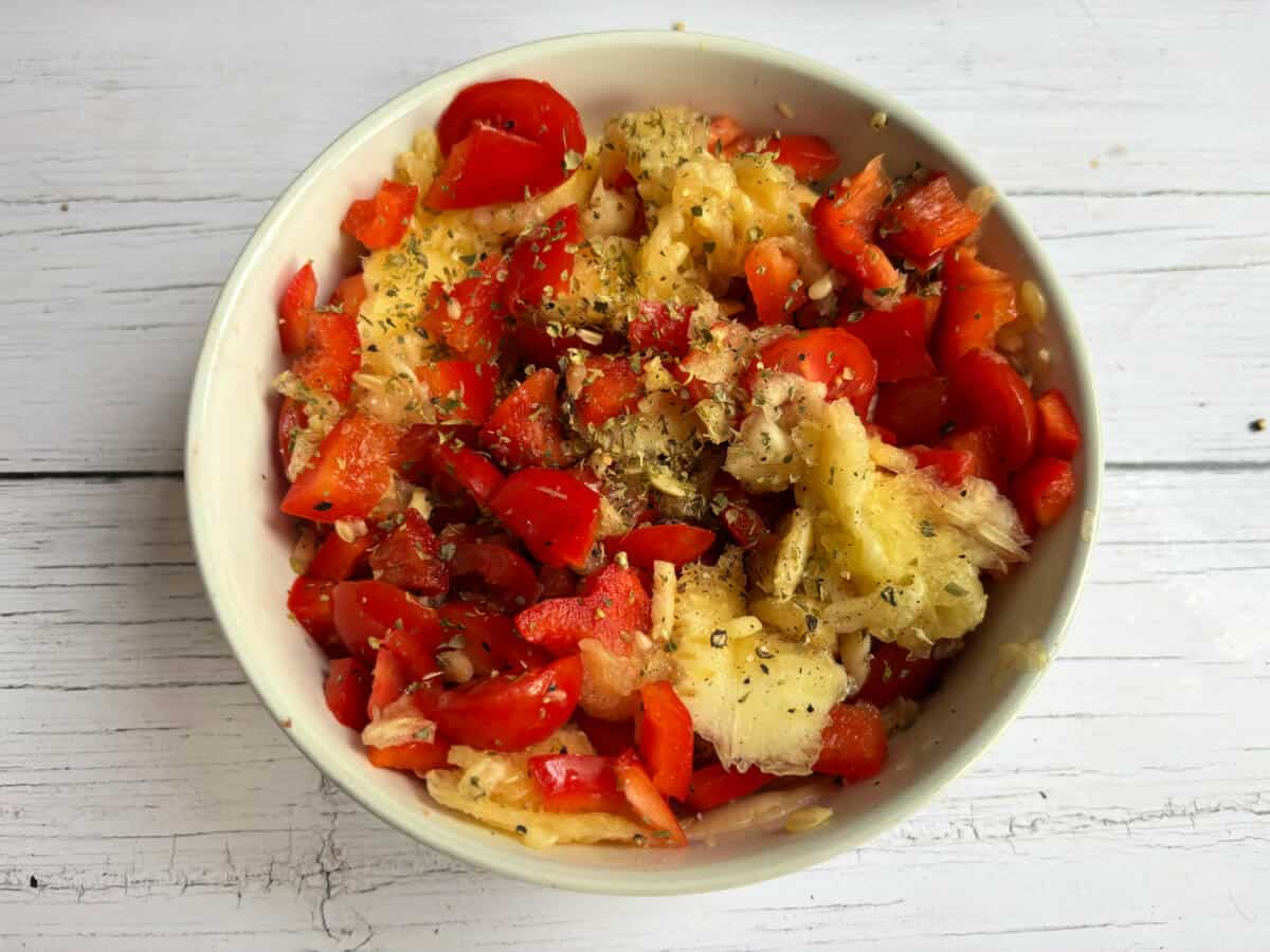 Courgette mixture in bowl with added herbs and seasoning.