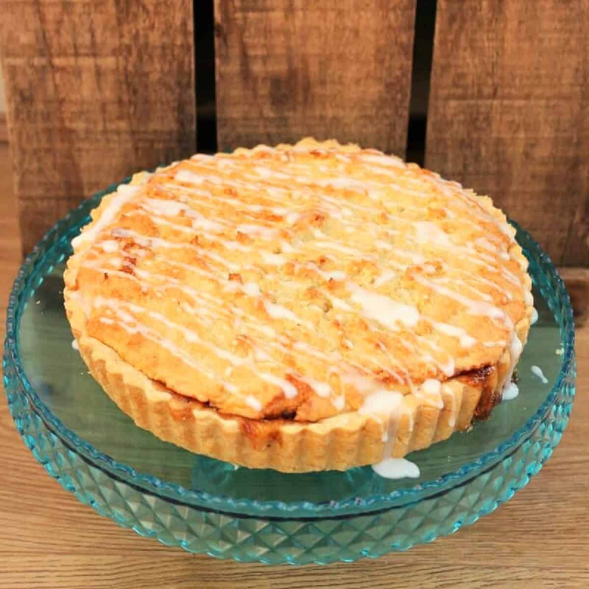 Bakewell tart on a clear blue cake stand.