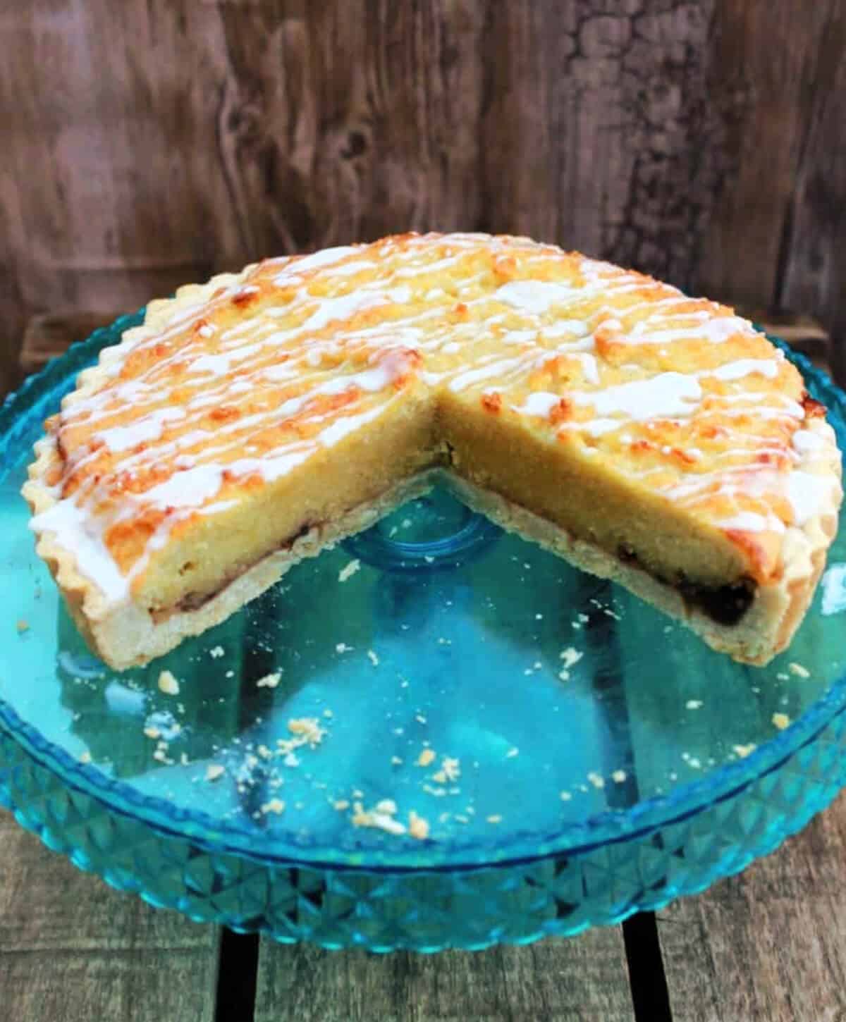 Tart on a cake stand with a large slice cut out, showing the layers inside.