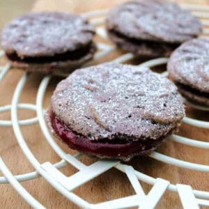 Viennese whirls with blackcurrant filling on white cooling rack.