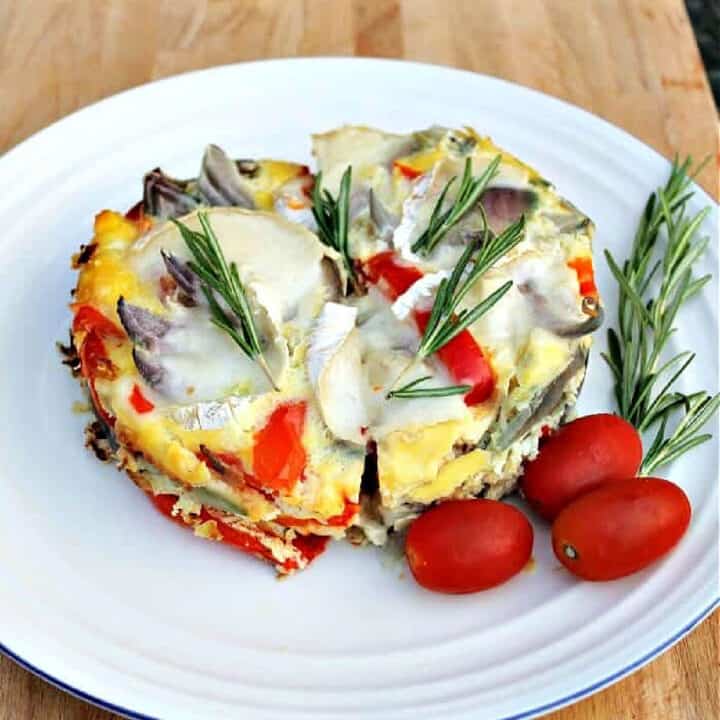 Frittata with red pepper and cheese, garnished with fresh rosemary, on a white plate.