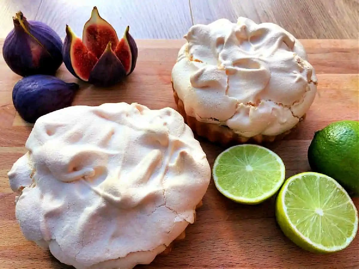 Close up of two meringue pies with limes and fresh figs.