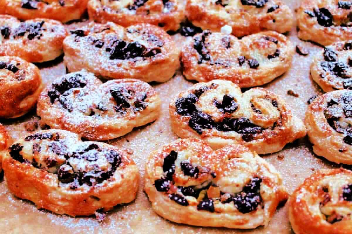 Palmiers dusted with icing sugar on a lined baking tray.