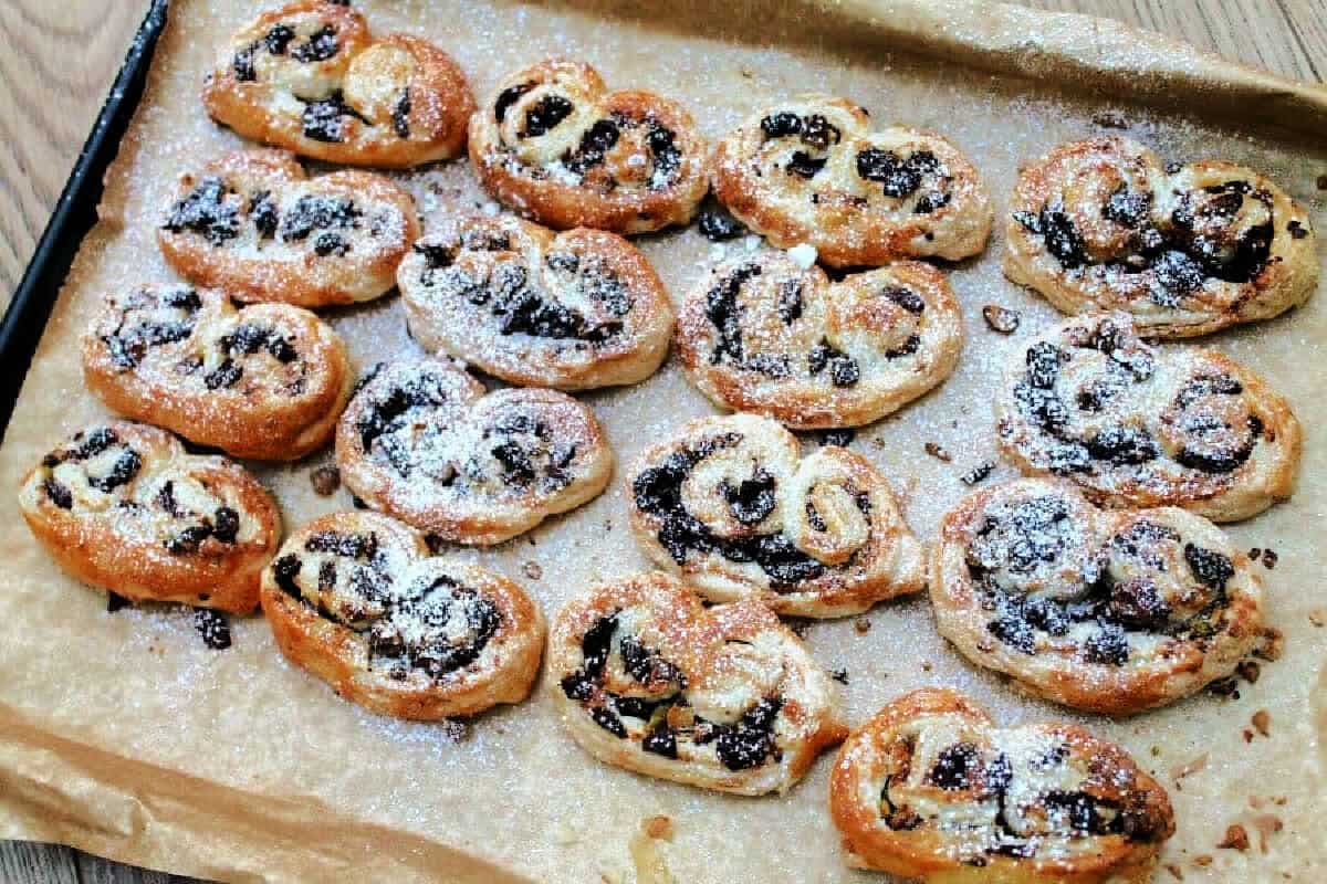 Palmiers dusted with icing sugar on a lined baking tray.