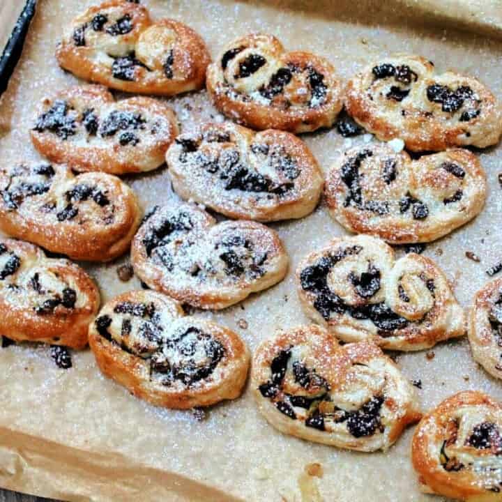 Palmiers dusted with icing sugar on a lined baking tray.