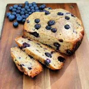 Banana and blueberry bread on wooden board, two slices cut.