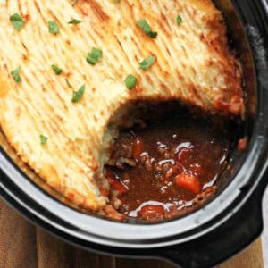 Close up of serving dish of cottage pie with one serving removed, showing the filling.