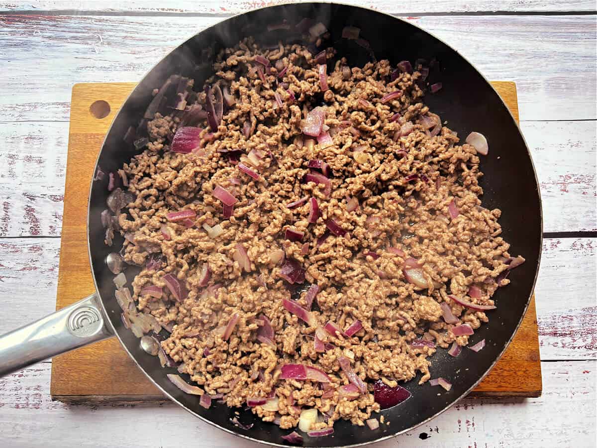 Minced beef and onions in a frying pan.