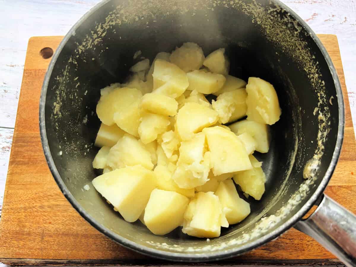 Cooked diced potatoes in a saucepan.
