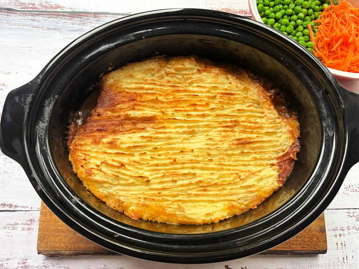 Cottage pie with browned mash topping, in slow cooker pot.