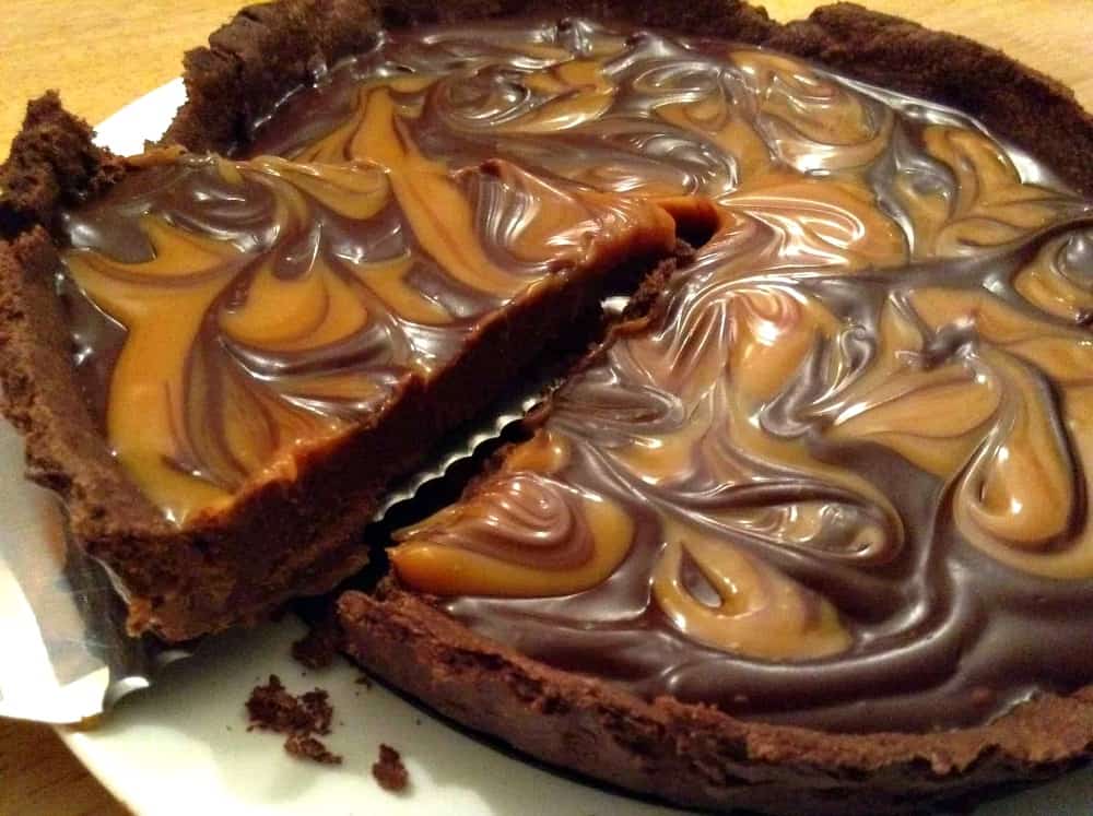Chocolate salted caramel tart. slice being removed, close up