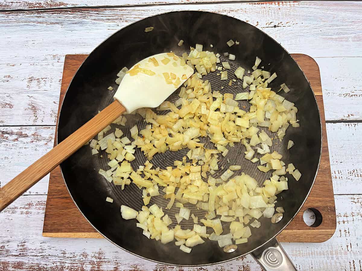 Chopped onions that have been fried, in a frying pan.