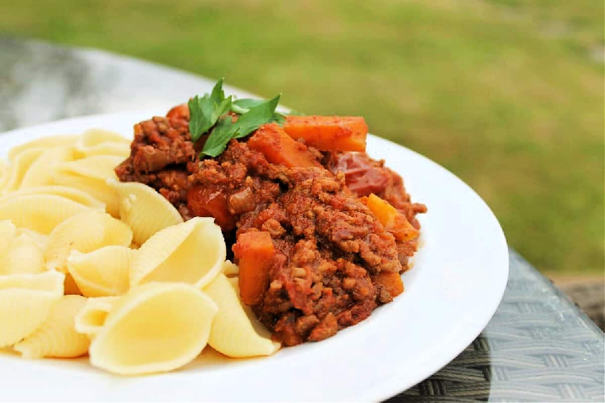 Side view of a plate of pasta bolognese.