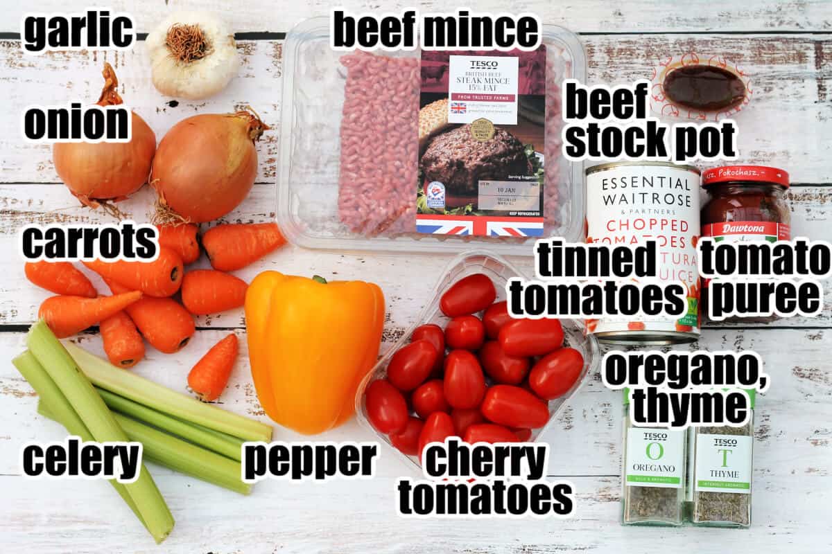 Labelled ingredients for bolognese sauce on a white table.