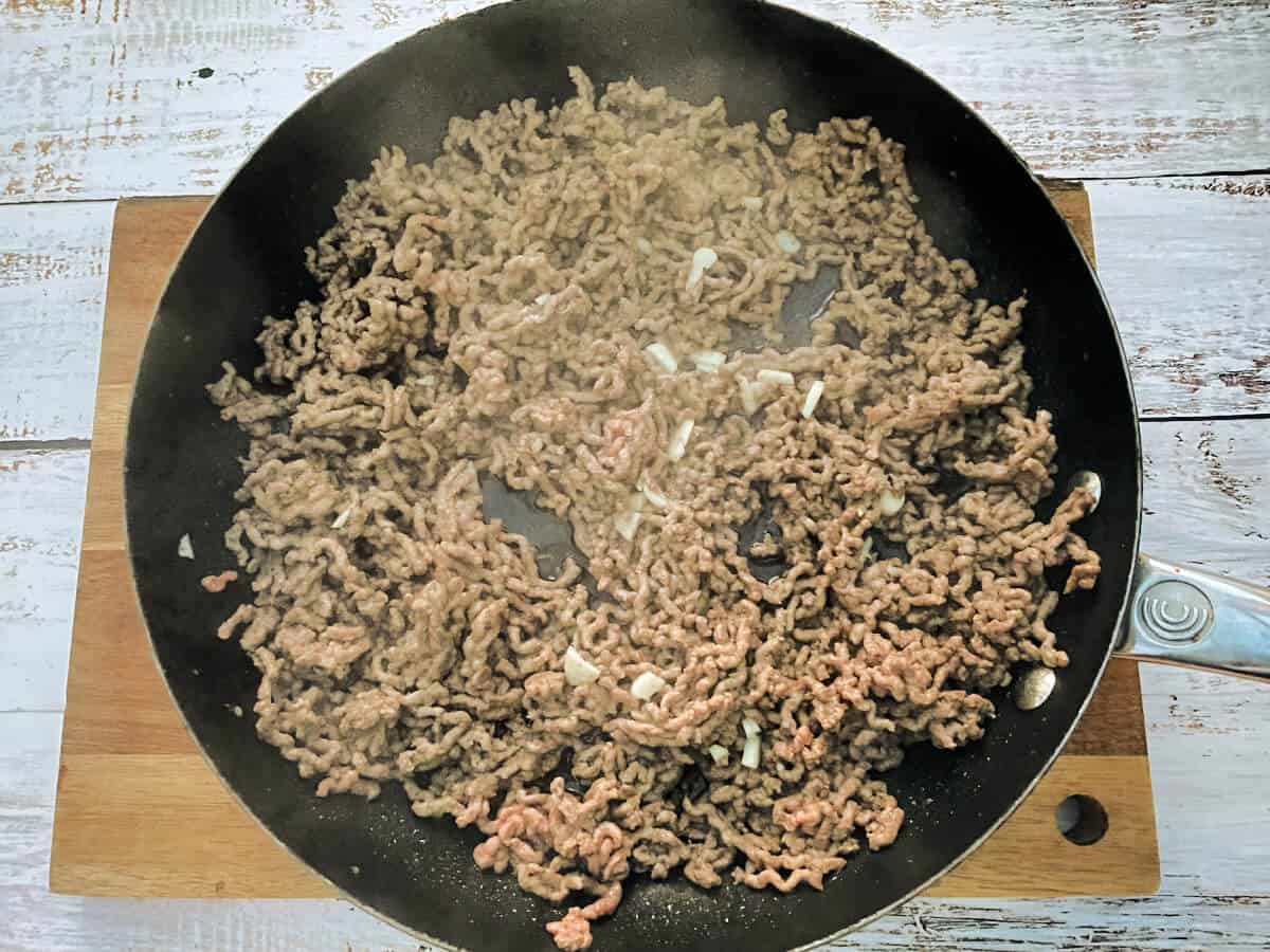 Frying pan with browned beef mince and garlic.