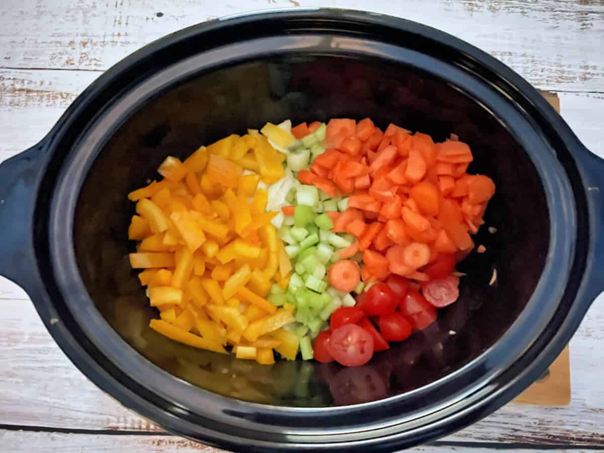 Slow cooker pot with colourful chopped vegetables.