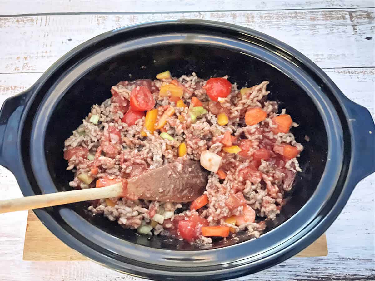 Slow cooker pot with Bolognese sauce ingredients, before cooking.