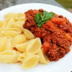 Close up of pasta bolognese garnished with basil.