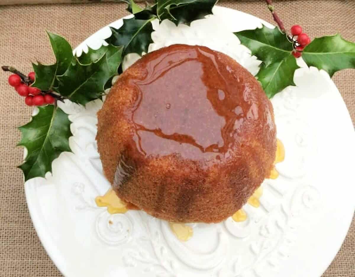 Steamed pudding on white plate with drizzled golden syrup.