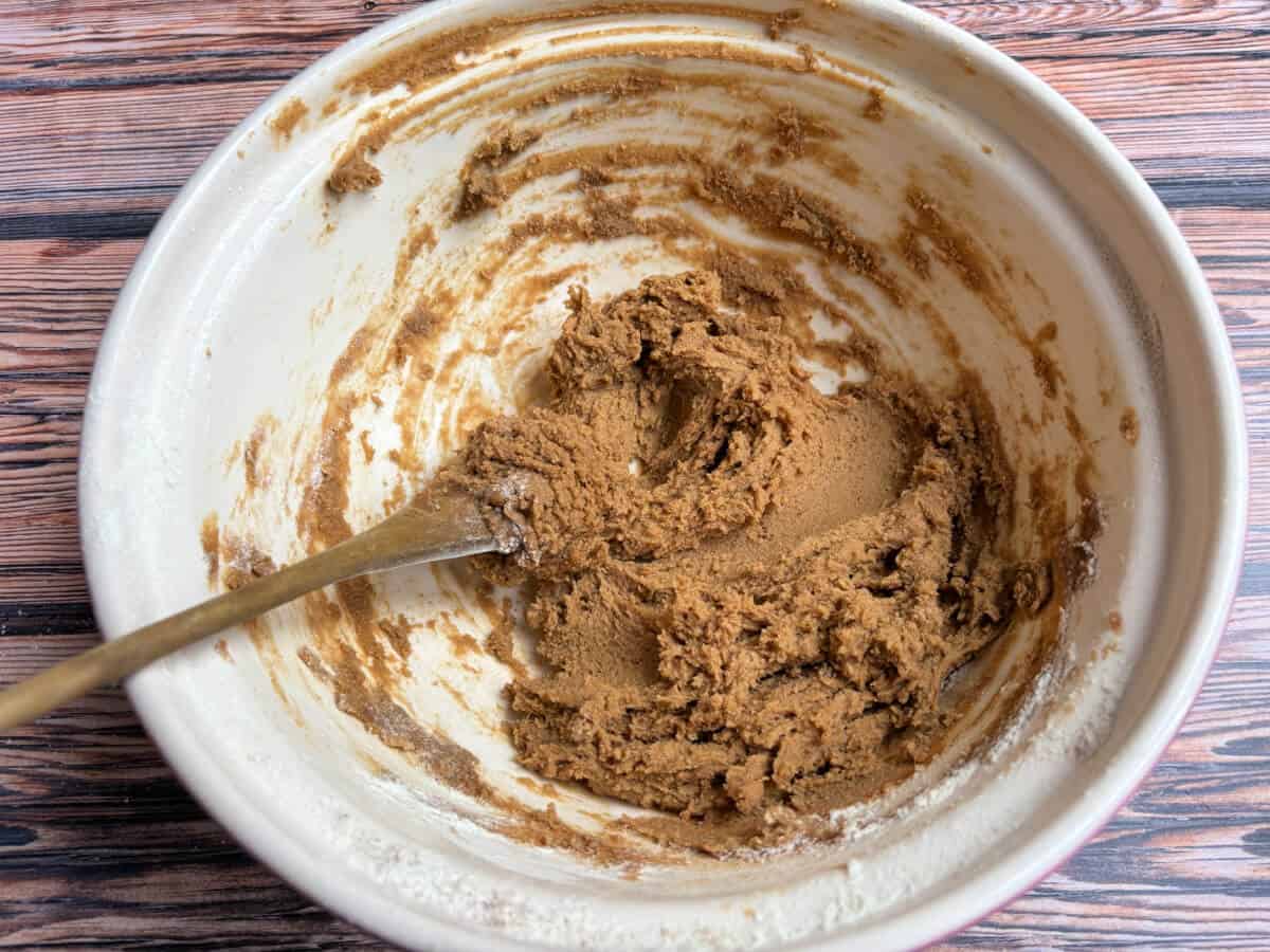 Sponge mixture in a bowl with wooden spoon, after adding flour and spices.