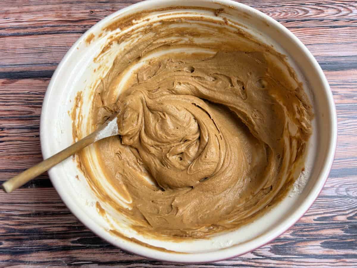 Cake mixture in bowl with wooden spoon, after adding all three eggs and mixing well.