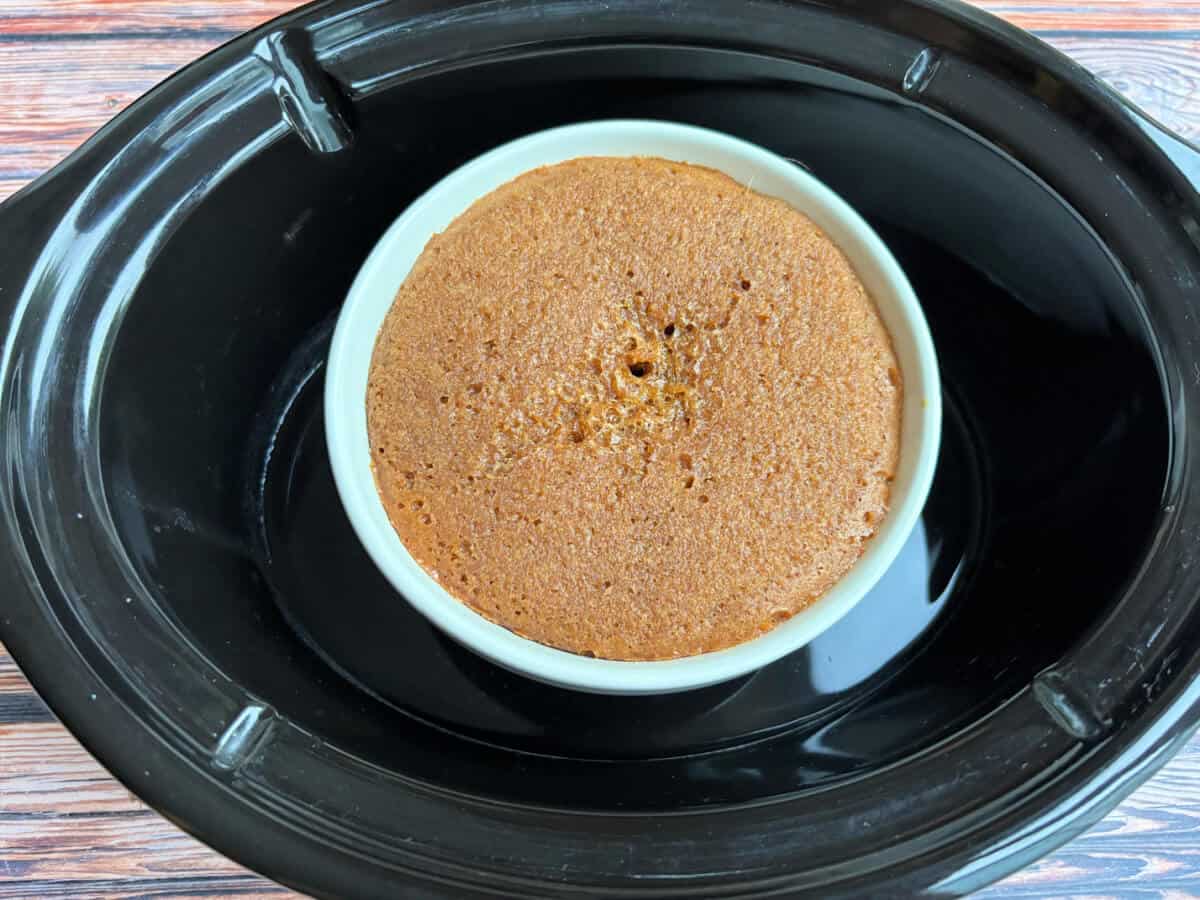 Baked gingerbread sponge in pudding bowl in slow cooker pot.