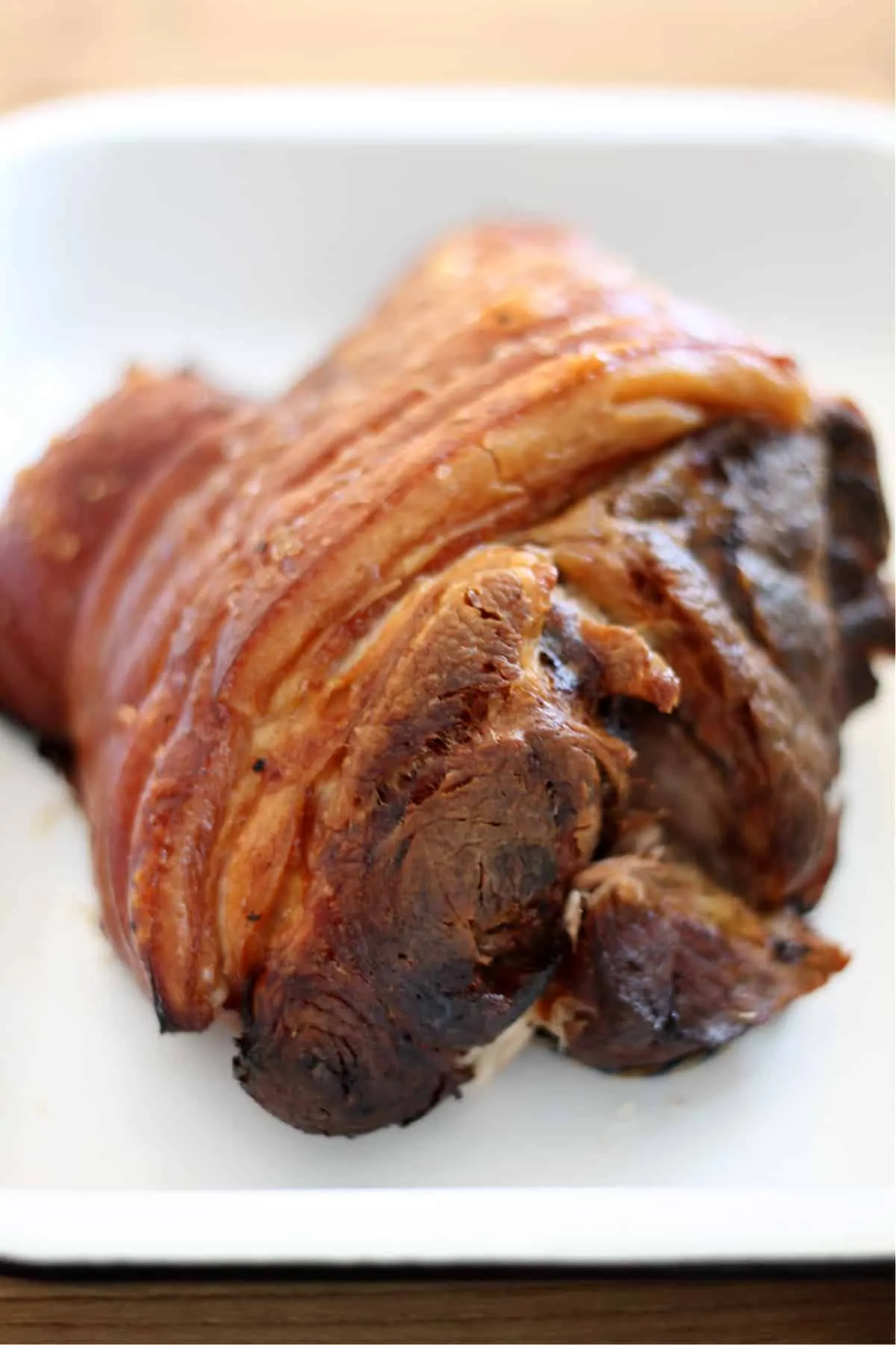 Close up of roasted pork in white serving dish.
