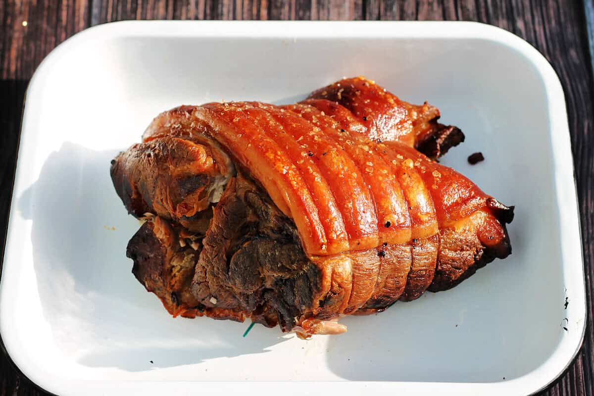Cooked pork joint with crackling in a serving dish.