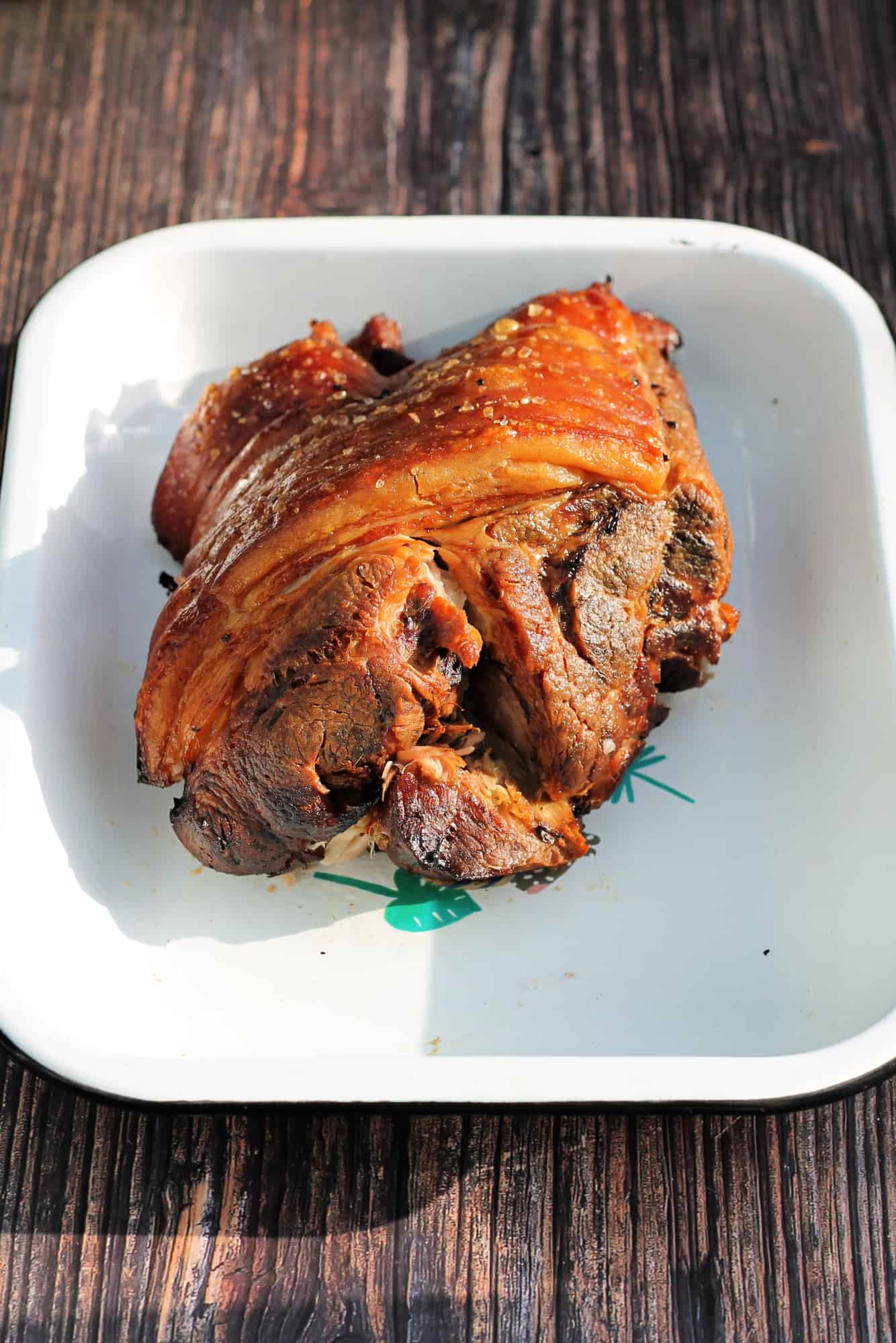 Roast pork with crackling in a white serving dish.