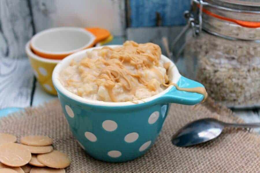 Rice pudding drizzled with caramel chocolate in a serving bowl with kitchen items in background.