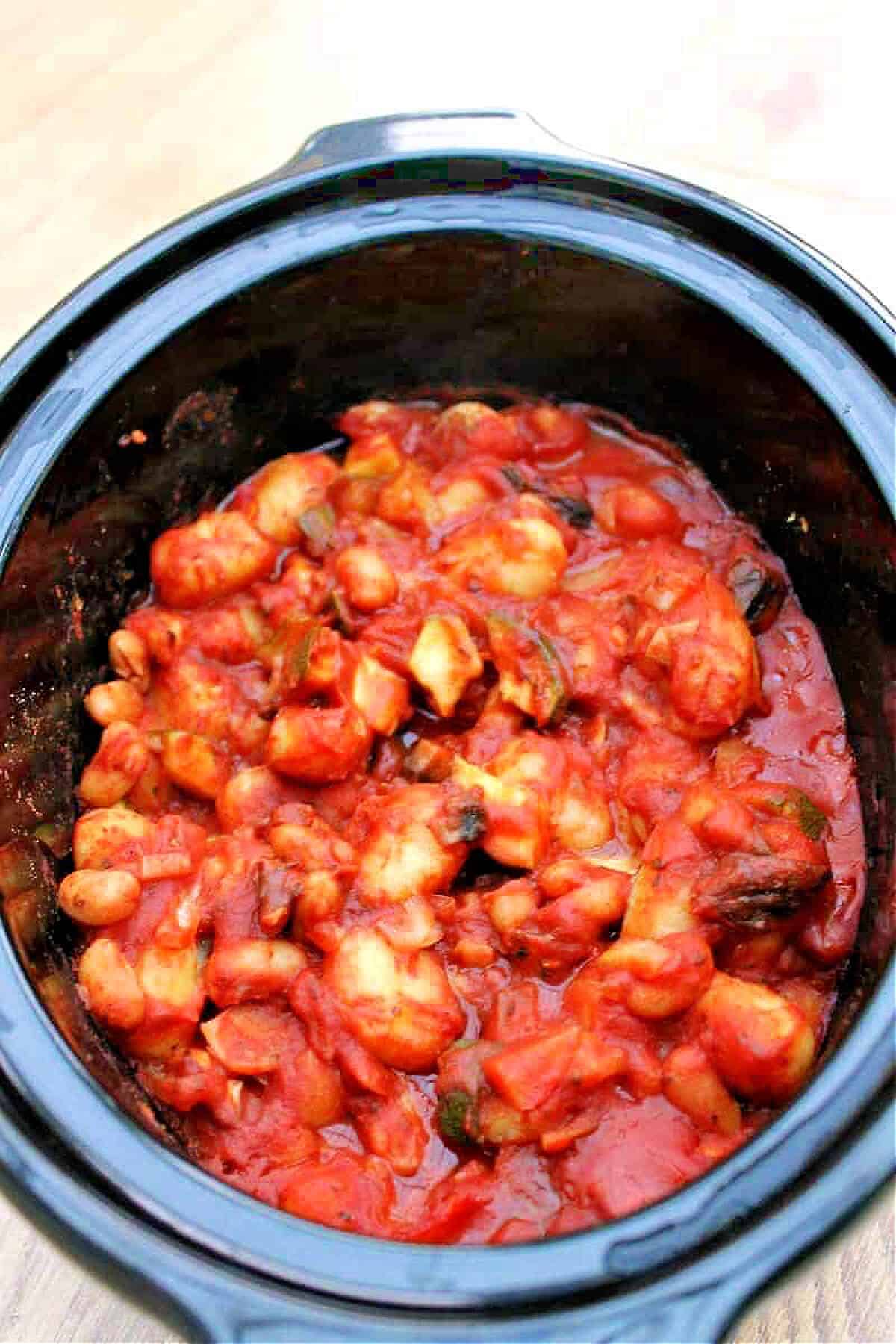 Gnocchi with beans and veggies in a tomato sauce in slow cooker pot.