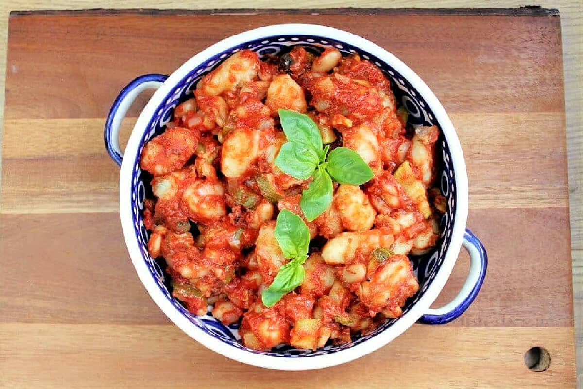 Serving dish of gnocchi in tomato sauce with cannellini beans.