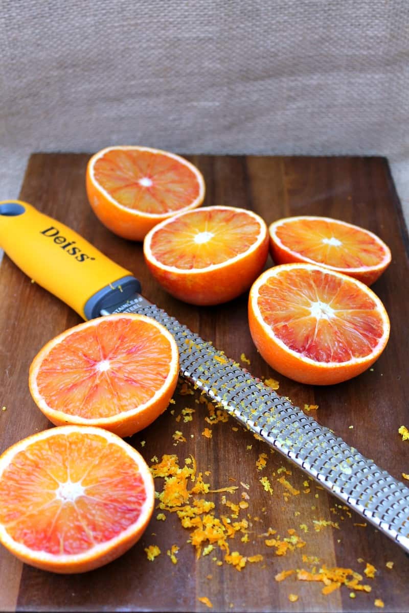 Blood oranges cut open on a board with grater.